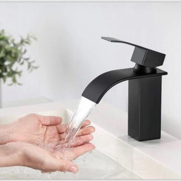 a person washing their hands under a kitchen tap
